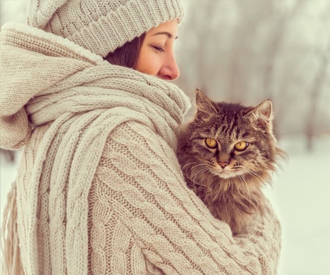 woman holding cat in snow